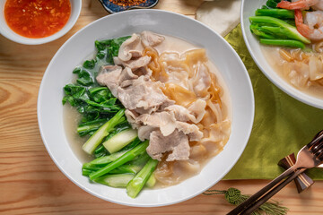 Wide Rice Noodles with pork and kale in Gravy Sauce  Served with condiments, chili powder , chili sauce and sugar. Asian food