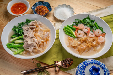 Shrimp Wide Rice Noodles and Pork Wide Rice Noodles with  kale in Gravy Sauce  Served with condiments, chili powder , chili sauce and sugar. Asian food.