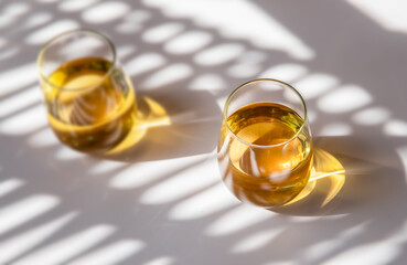 glass of white wine or apple juice, cider on white background with harsh shadows, natural light,...