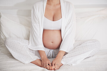 Baby on board. Cropped shot of a pregnant woman at home.