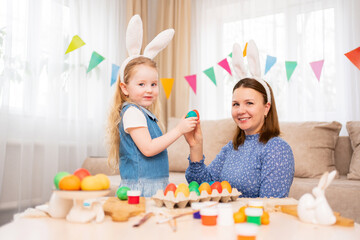 Obraz na płótnie Canvas mother and sweet daughter play with Easter eggs in game of who will break.