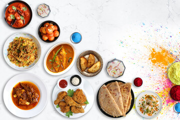 Assorted Indian Holi festival non veg food like Prawns masala, Laddo, Mutton Biryani, Mutton Curry, Fish curry, Fried Chicken, puranpoli, gujiya, gulab jamun with colorful background with copy space.