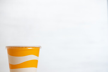 Yellow and white striped plastic cup for soft drinks with copy space
