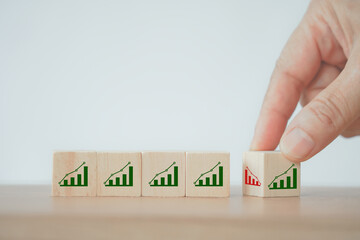 businessman's hand flipped decreasing graph to increasing graph icon on wooden cube block for development, growing business or income concept