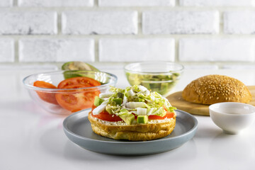 Vegetarian toast with cottage cheese, tomatoes, avocado, Chinese cabbage, pumpkin seeds and sesame seeds on a white table