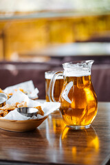 Glass mug and jug of beer with snacks in a cafe summer terrace