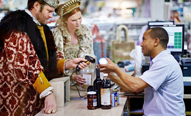 We have a coupon for that.... A king and queen buying groceries and paying at the cashier.