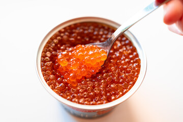 a spoonful of salted red caviar is taken out of the jar. delicacy. delicious canned fish. a...