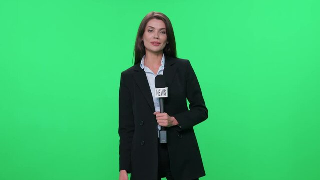 Female reporter in suit looks at the camera and speaks into a microphone on a green background, template for TV news agencies, journalist at work, breaking news.
