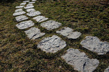 gray stone in a garden with a stone nature path to the arches near the lawns covered with snow. garden walkway made of slate boards side by side in lawn park architecture. ornamental, muddy