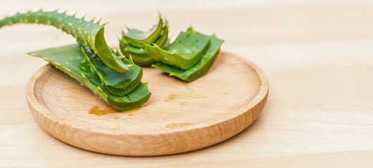 Fresh aloe vera leaves and slices of aloe vera on a wooden background.