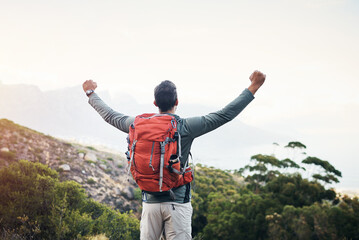 So this is what freedom feels like. Cropped shot of a cheerful young man lifting his arms in the air and looking into the distance while going for a hike up a mountain. - obrazy, fototapety, plakaty