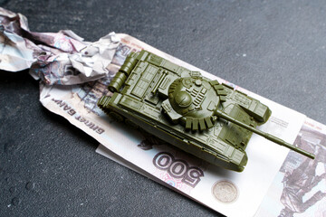 Economic crisis in Russia concept. Toy military tank on Russian rubles. War conflict in Ukraine,...