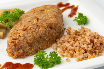 Cutlet with buckwheat with mushrooms on white plate