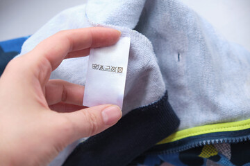 hand holding label with users manual of clothing item. clothes, laundry, people and housekeeping...