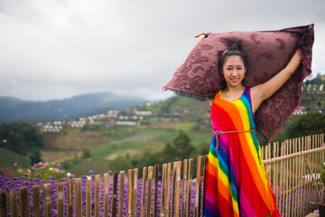 Beautiful Asian woman in colorful dress looking at view in flower garden park. 
