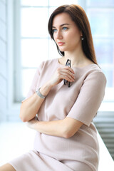 Stylish attractive young businesswoman with a lovely smile standing in the office grinning at the camera