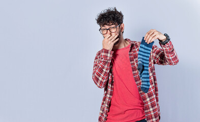 A man with a sock in his hand covering his nose, a guy with a stinky sock in his hand, smelly socks...