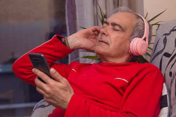 relaxed mature man with headphones and smartphone at home