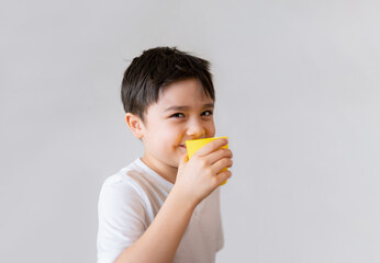 Portrait Young kid drinking fresh orange juice for breakfast, Isolated Happy child boy drinking glass of fruit juice and looking at camera with smiling face, Healthy kids food lifestyle concept