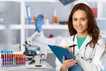 Serious scientist in lab coat a medical research laboratory. Student holding clipboard and taking notes summarising information for scientific report