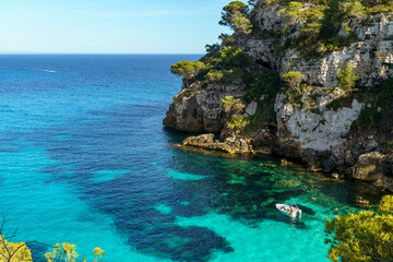 Turquoise waters of Cala Macarelleta with a small boat, in Menorca