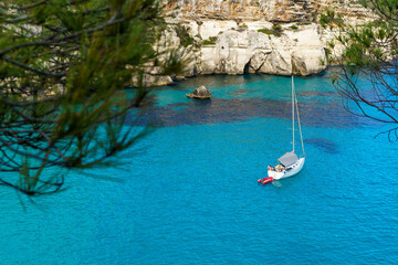 Fototapeta na wymiar Turquoise waters of Cala Macarelleta with a small boat, in Menorca