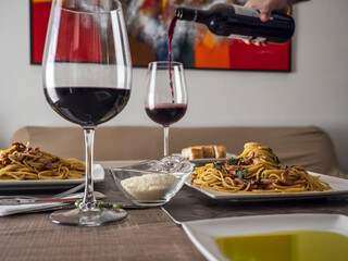 Pasta on the table with 2 glass of wine, bread and cheese