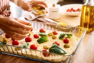 Obraz premium Woman cooking Italian focaccia bread at home. Selected fresh ingredients. Cooking process. Country style. Restaurant, hotel, cafe