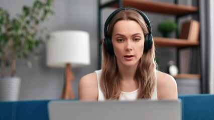 Modern woman in headphones talking online video call consulting remotely use laptop at home