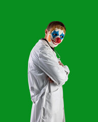 Not an honest doctor in a clown mask on a green isolated background. With a medical stethoscope....