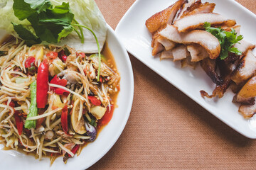 Top view of spicy papaya salad with salted crab and fermented fish. Delicious Som Tum Thai of Asian meal traditional style with charcoal-boiled pork neck ,Grill pork. Popular Thai street food. 