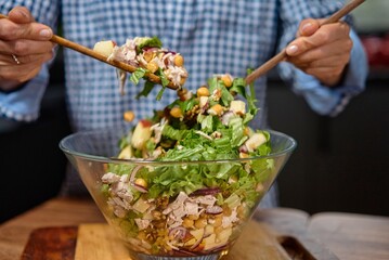 Young woman is preparing vegetable salad in the kitchen. Healthy Food. Vegan Salad. Diet. Dieting Concept. Healthy Lifestyle. Cooking At Home. Prepare Food. Clothe up.