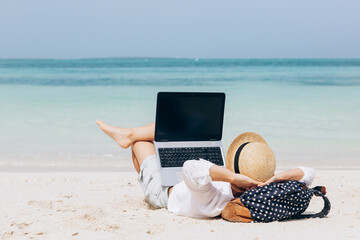 Young woman working, using laptop computer on a beach. Freelance work, vacations, distance work,...