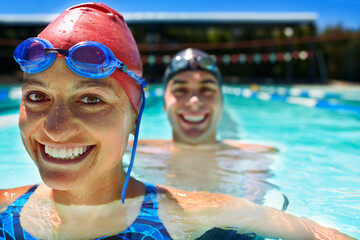 Friendly competition. Two swimmer standing in a pool smiling.