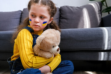 Sign of Ukrainian flag on child's cheek. Ukrainian geopolitics globe crisis. Little girl hold...