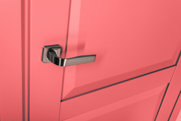 Closeup photo of colored pink door with handle in modern design