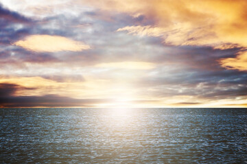 Beautiful sunset over wavy Baltic sea. Sunset sky background. Beautiful colors clouds. Warm color sunset scene. Evening cloudscape. Fluffy idylic panoramic view. Red and orange sunlight over the sky.
