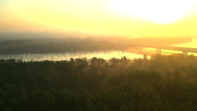 Flying over the river bank on a foggy morning. A railway bridge on the horizon