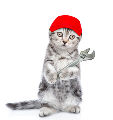 Funny kitten worker wearing red cap holds adjustable wrench. Isolated on white background