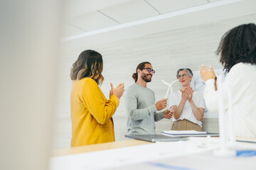 Successful designers applauding their colleague in an office