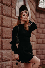 Beautiful girl in a black dress on the street