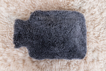 Colorful hot water bag standing on animal skin. There is an animal hide cover on the hot water bags.