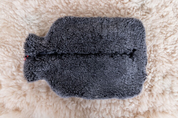 Colorful hot water bag standing on animal skin. There is an animal hide cover on the hot water bags.