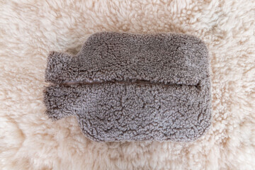 Colorful hot water bag standing on animal skin. There is an animal hide cover on the hot water bags.