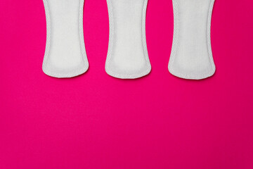 Close-up image of three women's sanitary napkins on a pink background leaving copy space. Concept of intimate hygiene of the woman when she is with the period.