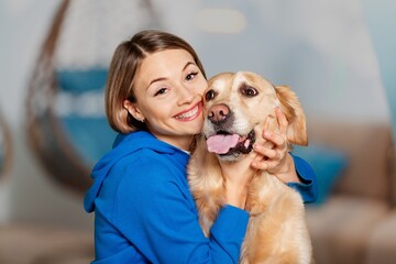 Portrait of cheerful young woman in casual outfit carrying her sweet fluffy dog