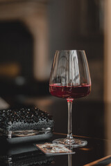 glass of red wine stands on a dark table next to a woman's bag. beautiful glasses for drinks, cafe, restaurant, free space