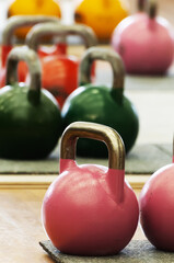 Naklejka na ściany i meble Kettlebells or cast-steel balls with handle of various colors and weights on gym floor