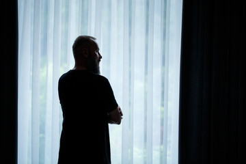 Male profile, a businessman stands against the background of a large window